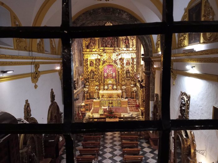 El convento de Santa María de Jesús, ubicado en la calle Águilas de Sevilla capital, muestra desde este fin semana su tesoro patrimonial a través de una magna exposición que lleva por título '500 años de oración. Monasterio de Santa María de Jesús', patrocinada por Fundación Unicaja, en conmemoración por los cinco siglos de presencia de la Orden Clarisa. Una imagen de Luisa Roldán 'La Roldana', con la advocación de Santa María Jesús, que preside el retablo mayor que ensambló Critóbal de Guadix en el siglo XVII; un magnífico belén realizado, casi a tamaño natural, por la citada escultora y que se encuentra en la sacristía del convento o un artesonado de casetones son algunos de los elementos artísticos del vasto patrimonio que se exhiben en esta muestra, que se podrá visitar hasta el día 30 de junio. Además del monasterio conventual, se exhibirá parte del interior de la clausura, con la musealización y piezas artísticas del tesoro de la comunidad clarisa, con esculturas, pinturas, ornamentos, orfebrería, bordados y documentación histórica. En relación a esto último, el visitante podrá ver en el coro alto varias dalmáticas bordadas entre los siglos XVII y XVIII y el manto de la Virgen del Rosario --abadesa perpetua--, con un diseño muy colorido y representaciones de aves, entre ellas pavos reales. Se trata de una rica pieza textil que evoca a los mantones de Manila. En ese mismo espacio se puede contemplar la sillería del coro y varias imágenes del Niño Jesús, una de ellas atribuida a Juan de Mesa,así como un pequeño crucificado del imaginero Jorge Fernández Alemán, mientras que en el coro bajo se muestran elementos de orfebrería de carácter litúrgico y la bula papal concedida al monasterio de las clarisas. Muy cerca de este lugar destaca un retablo que representa el calvario de Jesús y la talla de San Pancracio, que cuenta con miles de devotos. En el presbiterio "merece la pena detenerse en los azulejos de la pared", junto al portentoso retablo mayor, "vestigios de la primera etapa del monasterio, en 1589", tal y como afirma Francis Segura, historiador del arte y uno de los guías de la exposición. "En esta muestra podemos ver lo que normalmente no vemos por el concepto de clausura, con lo que no solo se muestra el patrimonio sino esta forma de vida conventual". En esa línea se ha manifestado el comisario de la muestra, Antonio Librero, que ha destacado que con la iniciativa "hemos conseguido sacar la exposición de su propio confinamiento". La muestra pretende rendir así homenaje a los cinco siglos de presencia de la Orden Clarisa en la ciudad. "Son 500 años de conventualidad y de amor a Sevilla, y ahora exponemos parte de nuestro legado, heredado de nuestras hermanas", como subraya la abadesa del convento de la calle Águilas, Luisa Durán. Asimismo, pinturas de Nuria Barrera, Irene Dorado, Javier Jiménez Sánchez-Dalp, Juan Miguel Martín, José Tomás Pérez Indiano, César Ramírez están a la venta en la exposición. Son obras artísticas centradas en rincones y detalles de la Clausura. La visita será en grupos reducidos, siguiendo así la normativa en materia de Covid-19 y guiada, en horario de martes a sábado, de 13,00 a 15,00 horas y de 16,00 a 19,30 horas. Los domingos abrirá al público de 12,00 a 15,00 horas y de 16,00 a 19.30 horas, mientras que los lunes permanecerá cerrada al visitante. La compra de entradas, será exclusivamente vía digital, a través de 'exposicionclarisas.com'.